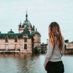 Bond Horse - woman facing beige and green concrete building and body of water