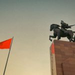 Hero Horse - a statue of a man riding a horse next to a red flag