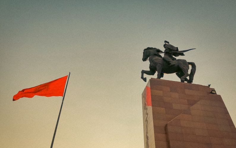 Hero Horse - a statue of a man riding a horse next to a red flag