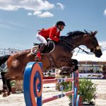 Jumping Horse - brown horse with red and white helmet riding on brown horse during daytime