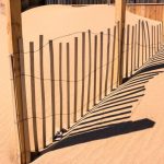 Rough Terrain - a fence in the sand with a pair of shoes on it