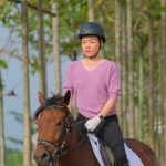 Helmet Equestrian - woman in pink crew neck t-shirt riding on brown horse during daytime