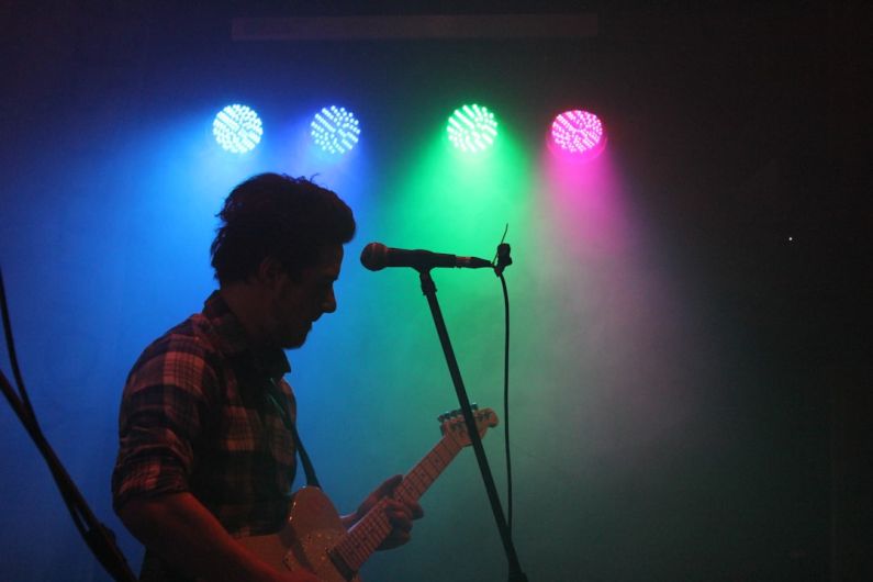 Performance Breeding - man playing guitar with stage lights